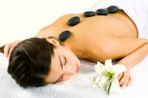 Portrait of young woman at the day spa with black stones on her bare back